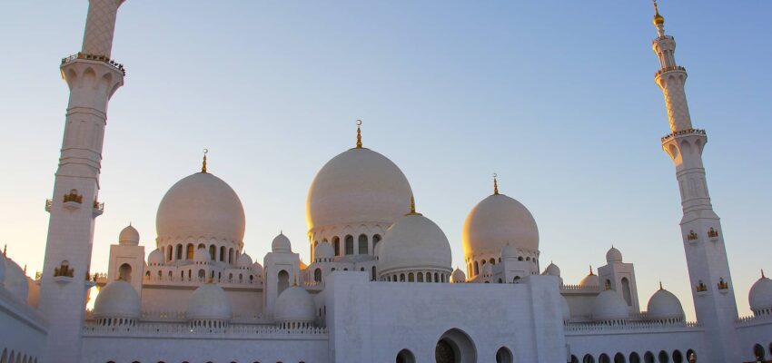 Mosquée blanche avec dômes et minarets au coucher du soleil.