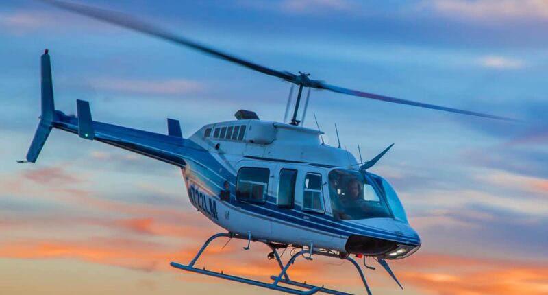 Hélicoptère Bell 206 en vol avec couché de soleil