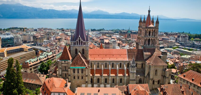 Vue aérienne Cathédrale de Lausanne, toits rouges, lac, montagnes.