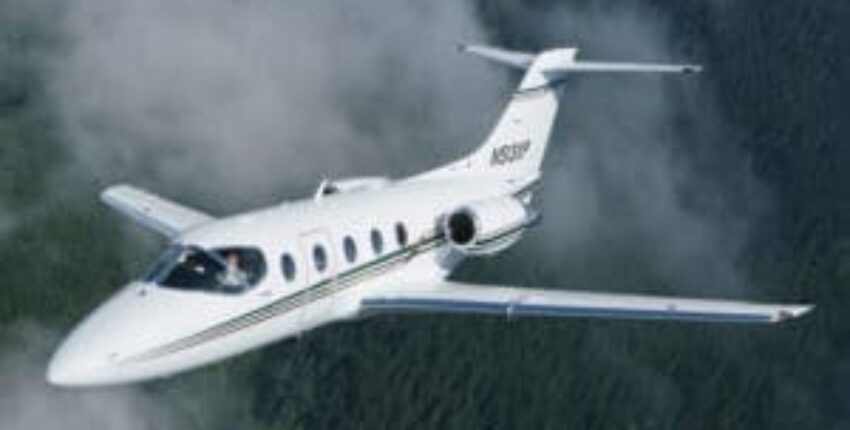 location de jet privé: BEECHJET 400 volant au-dessus d'une forêt