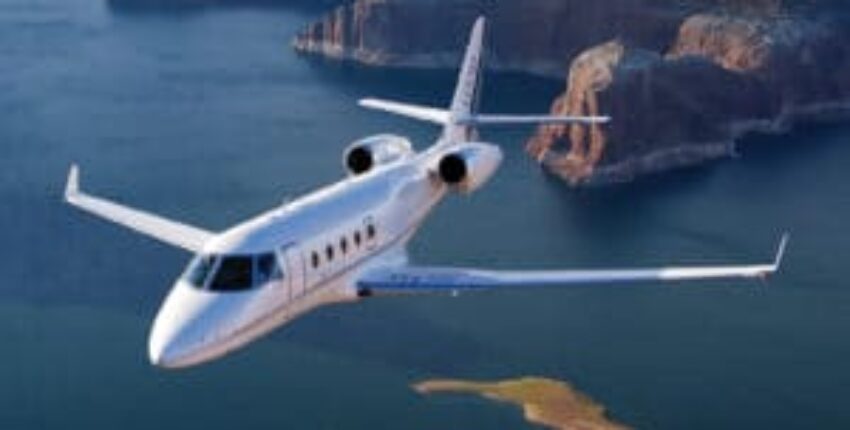 Location jet privé ASTRA volant au-dessus d'eau et falaises.