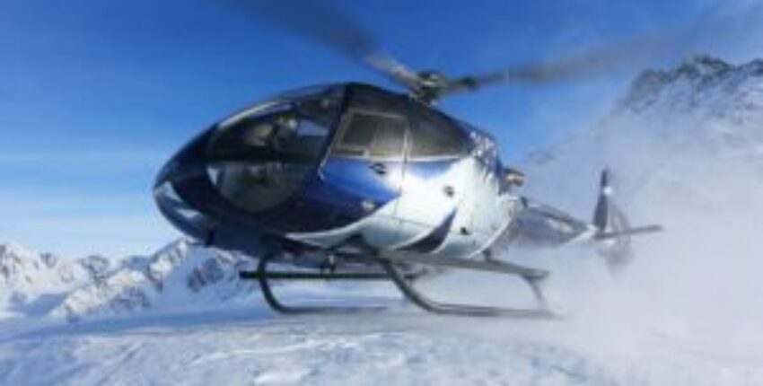 EC 130 B4 : Hélicoptère bleu au-dessus des montagnes enneigées.
