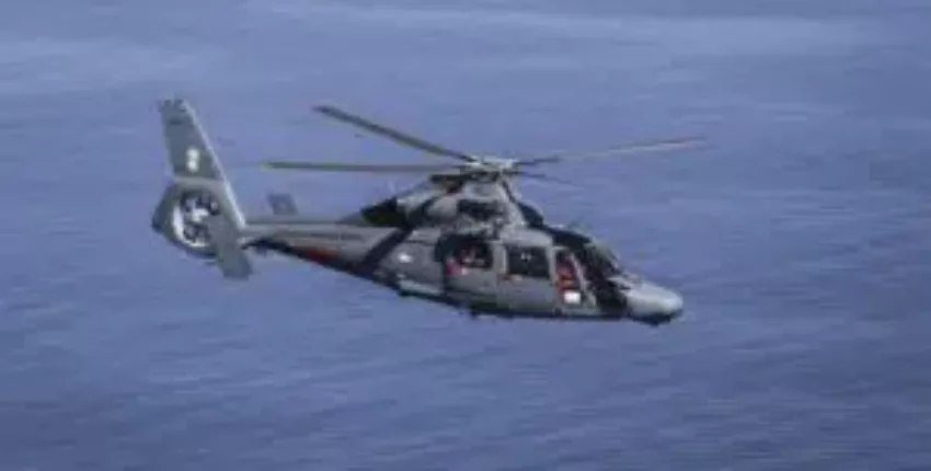 Hélicoptère DAUPHIN AS 365 survolant l'eau.